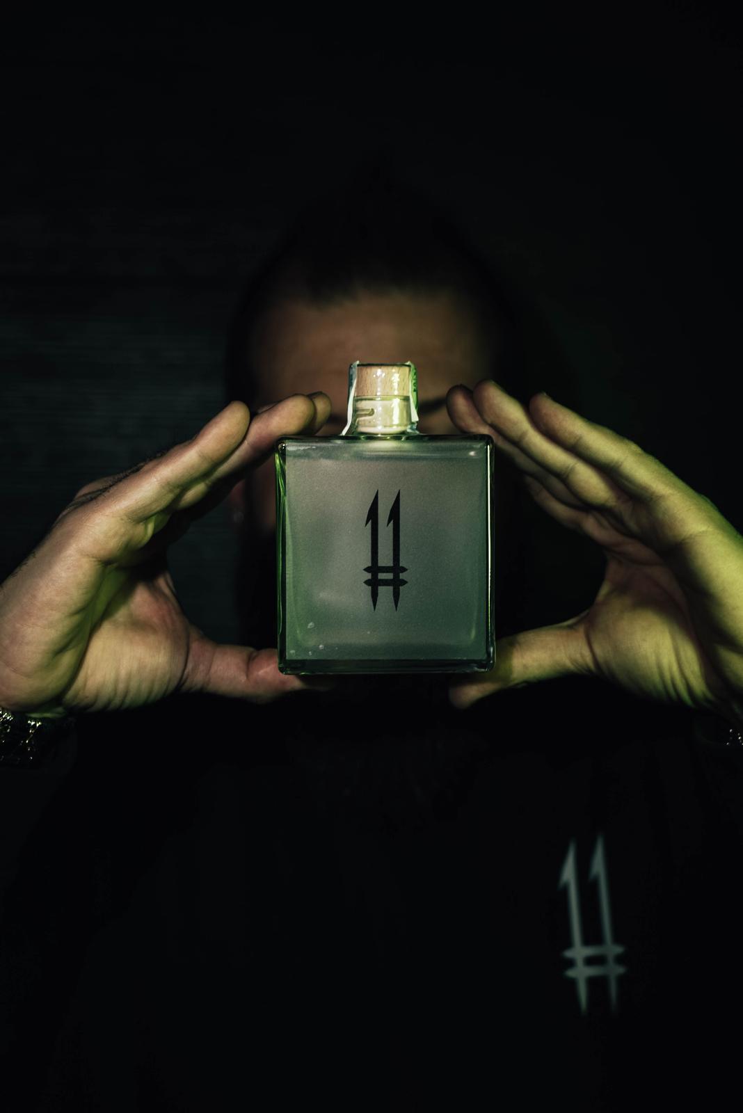 Alex, fondatore di N.11drink, tiene N.11 London Dry Gin — Il Guardiano davanti al volto