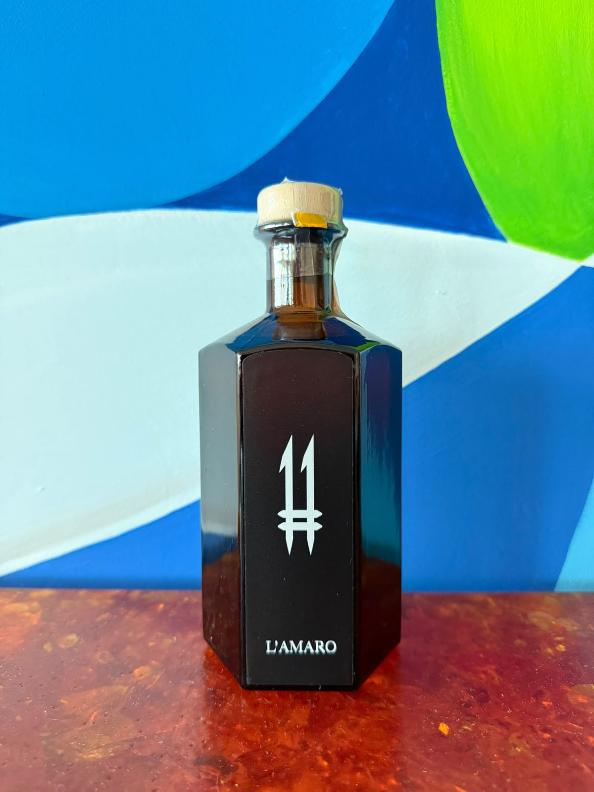 N.11 L'Amaro — L'Oscuro — Bottiglia esagonale scura di N.11 L'Amaro L'Oscuro con logo 11 bianco