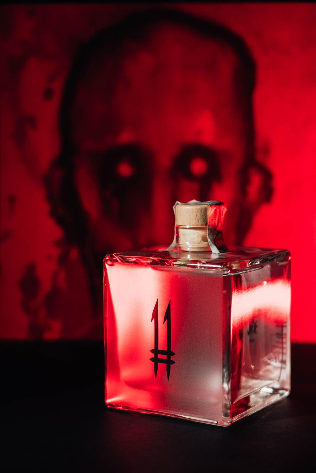 N.11 London Dry Gin — Il Guardiano davanti a un volto dipinto, luce rossa