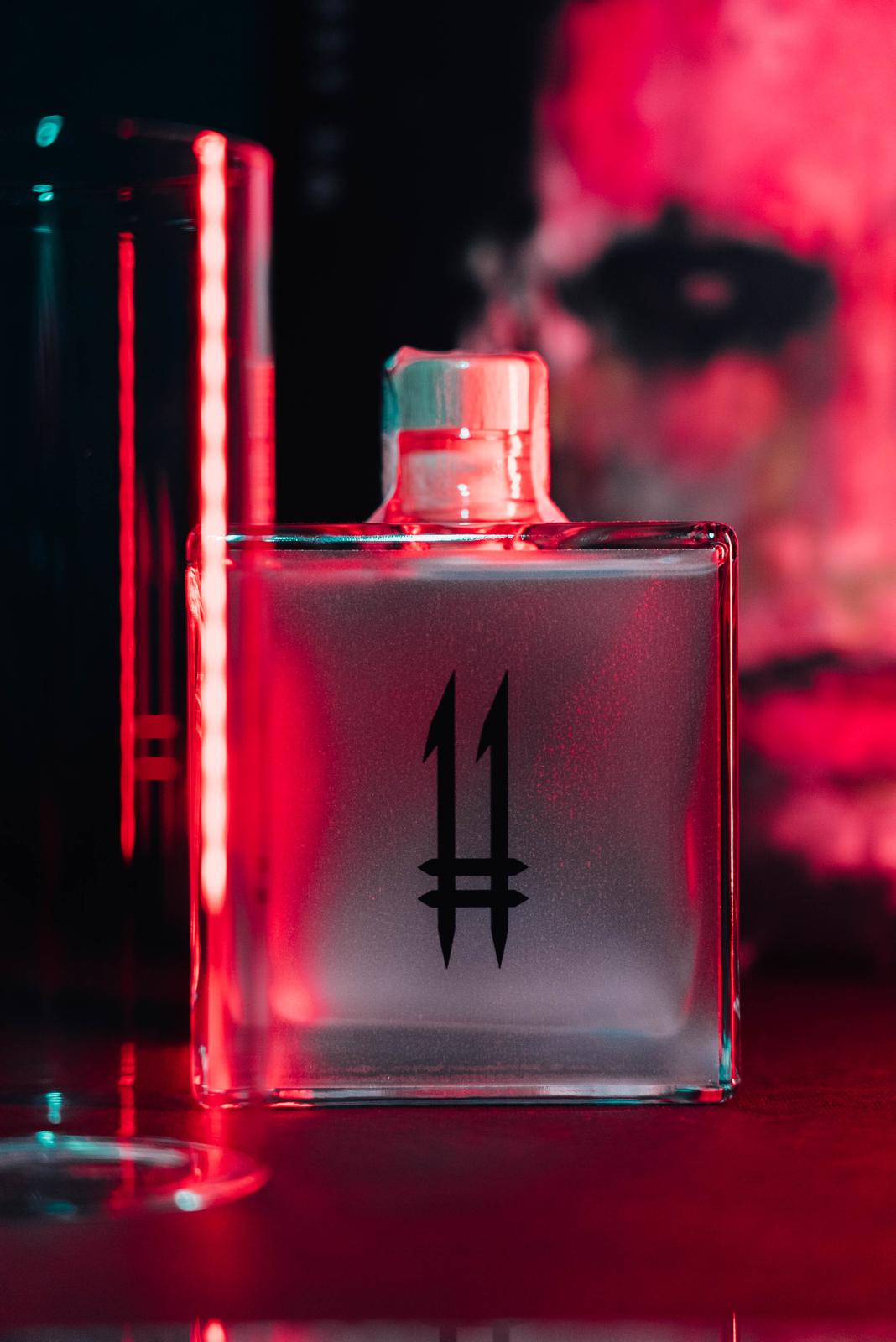 N.11 London Dry Gin — Il Guardiano accanto a un bicchiere, luce rossa