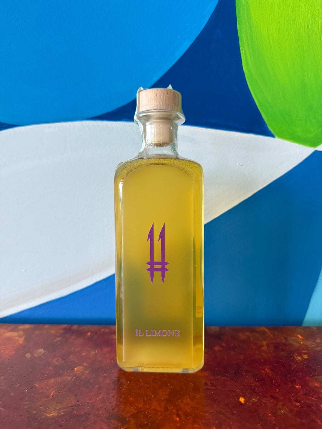 N.11 Il Limone — Il Seduttore — Bottiglia quadrata alta di N.11 Il Limone Il Seduttore con liquore giallo e logo 11 viola